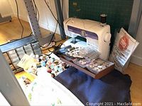 Brother XL-5500 machine on table with foot pedal, power cord, cutting mat, thread spools and bobbin organizer