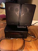 Front view of CD receiver unit with speakers on top and visible wires