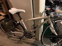 Full left-side view of the white Specialized Dolce Elite bicycle leaning against wall