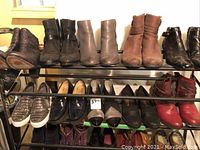Shelves showing various pairs of women's shoes and ankle boots, including black, brown, taupe and snakeskin boots, silver slip-ons, loafers and heels.