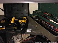 Drill, charger, battery pack and open metal toolbox with hand tools on shelf