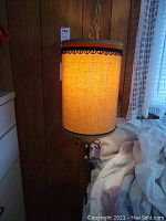 Full view of lit vintage hanging lamp with fabric cylindrical shade and chain suspension.
