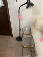 Side tables placed beside a sofa with floor lamp behind on a carpeted floor under indoor lighting.
