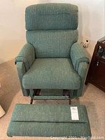 Front view of the green fabric recliner chair showing padded backrest and armrests with footrest placed in front.