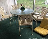 Full kit showing round table with four matching cast aluminum chairs on a green carpeted floor.
