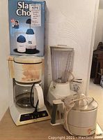 Lot shows Hamilton Beach blender, Mr. Coffee coffee maker, Toastmaster juicer, and Slam Chop food chopper in original box.