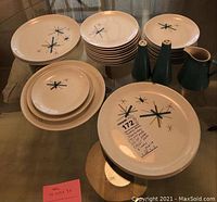 Full view of all dishware: three sizes of plates and accessories salt and pepper shakers and pitcher all with Atomic North Star pattern.