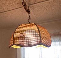 Photo of the vintage wicker hanging light turned on, hanging from a chain on ceiling