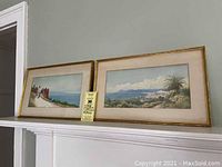 Pair of framed landscape watercolors resting on a white shelf, showing their full size and frame style.