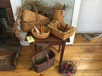 Overall view of vintage woven baskets of different sizes on and around a wooden table in a room with rustic wooden floor