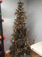 Full view of decorated and lit 6-foot artificial Christmas tree with primitive style decor in a room corner.