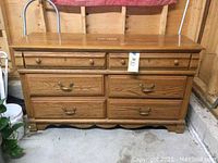 Front view of the wooden double dresser showing six drawers and metal handles, with some wear visible.