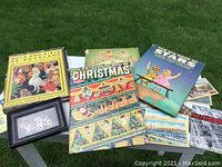 Photo showing four vintage children's books with colorful illustrated covers, framed basset hound print, San Francisco ephemera including booklet and postcard laid out on table