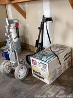 Boxed Step2 Garden Hopper garden cart alongside two golf caddies including Wilson branded one, items appear stored in garage