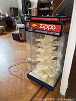 Zippo clear acrylic display case with white holders and red and blue Zippo branding