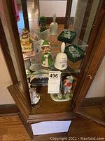Display cabinet with various crystal ornaments, ceramic bell and figurines arranged on shelves.