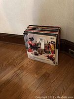 Photo of stacked vinyl records with cover art featuring various figures in costumes, likely a Rolling Stones album.
