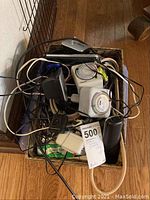 Wicker basket filled with electric timers, surge protectors, cords, and cordless phone handset