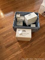 Photo showing multiple boxes from Department 56 Heritage Village Collection in a crate and some boxes outside on wooden floor.