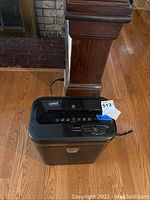 Front view of Staples paper shredder showing top control panel and front waste bin door.