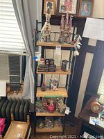 Tall black metal frame shelf unit with five wooden shelves, displayed with various household items, sold without contents.