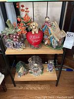 Wide angle view of shelf with ceramic votives and faux flowers showing six items for sale.