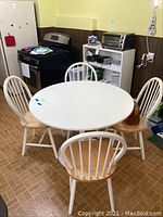 Round white kitchen table with four matching wooden chairs with white painted backs and legs, natural wood seats in a kitchen setting. Images show table dimensions and surface condition.