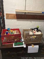 Photo showing two plastic crates on a black dresser with assorted items including a Mickey Mouse plush toy.