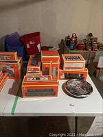 Overview of boxed Lionel train cars and accessories on table with chrome-rimmed train clock