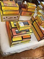 Stacked Rail King MTH Electric Trains original boxes on a bed with yellow and orange Rail King branding.