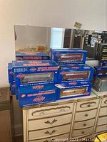 Stack of six blue Atlas Custom Supreme boxes on dresser, partial reflected in mirror