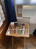 Photo of a wooden tray table with multiple women's watches and a men's wallet in original box labeled 'Rolex'. Variety of watch styles and colors.