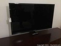 Front view of TV on cabinet with remote placed below