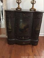 View of closed front showing chest with one drawer and three doors, painted scenes on each door from top to bottom, floral embossed wood details.