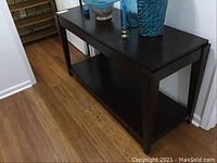 Full view of the dark brown wooden console table showing its rectangular shape and lower shelf.