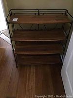 Front view of metal frame shelf with four wooden surfaces showing wood grain and minor smudges on top.