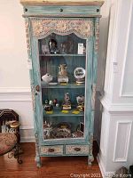 Front view of full cabinet showing carved crown, glass door, shelves, drawers and finish
