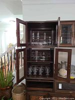 Glassware displayed inside a dark wooden cabinet showing stemmed glasses and decorative items