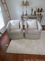 Front view showing both chairs side by side on a white rug with faux fur pillows