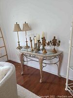 Full view of the living room table with glass insert top and items placed on top (items not included). The ornate carved legs and metal scrollwork visible beneath the marble frame.