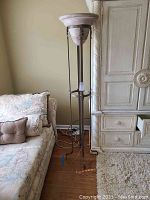 Full view of tall floor lamp next to sofa and cabinet showing lamp height and surrounding context.