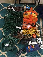 Overview of extension cords in multiple colors and lengths, coiled, and two blue tarps folded.