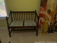 Full view of wooden bench with two floral cloth seat cushions in cream, blue, orange, green, and red.