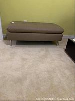 Full view of the faux leather bench showing brown padded top and metal legs.