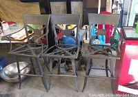 Three metal swiveling bar stools grouped together, showing overall condition with rust and wear in a garage setting.