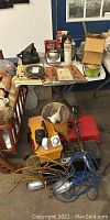 Wide view of garage area with toolboxes, motor oil, funnels, and various small supplies on a table and floor.