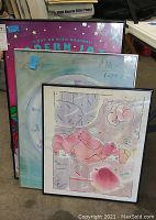 Three framed prints leaning against storage boxes