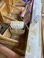 Somerset prefinished hardwood flooring planks wrapped in plastic and stacked along attic beams with other flooring materials around.