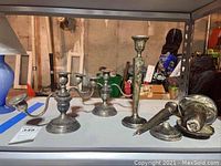Photo showing two vintage sterling silver cement filled candle holders and several broken pieces on shelf with background of basement setting