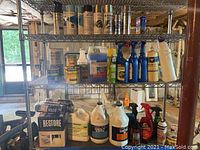 Metal shelving unit with multiple bottles and cans of cleaning products and wood finishes.